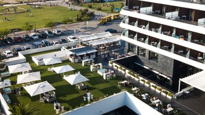 Un hotel moderno con piscina en la azotea, zona de comedor al aire libre y vistas a la playa y al océano.