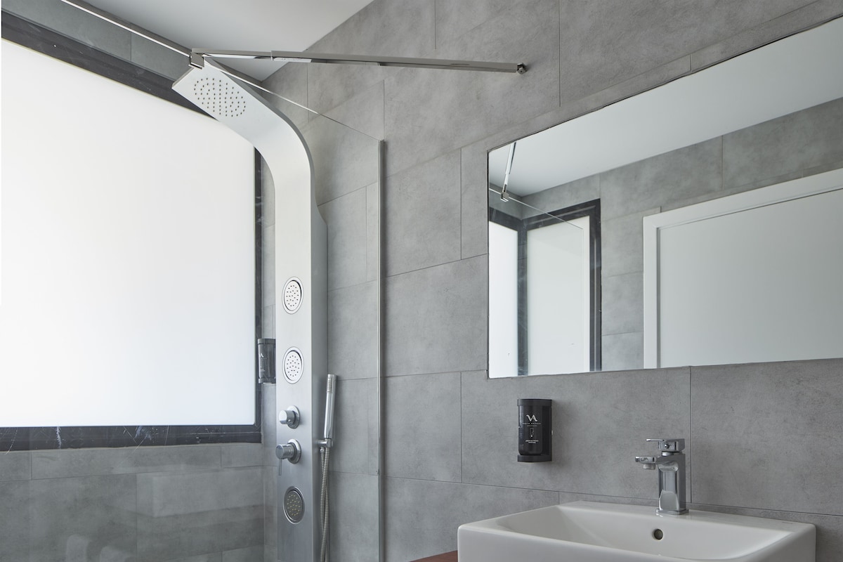 Un baño moderno con ducha, lavamanos y espejo.