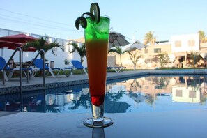 A cocktail glass with a lime garnish on a poolside table.
