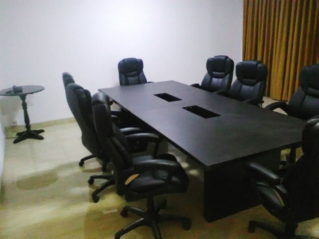 Un salón de conferencias con una larga mesa y seis sillas de oficina negras.