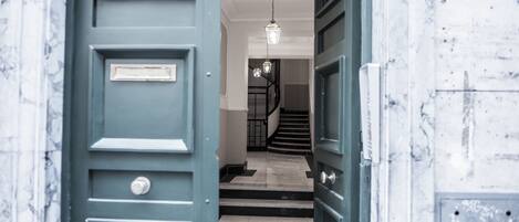A hallway with a blue door, a staircase, and a hanging light fixture.