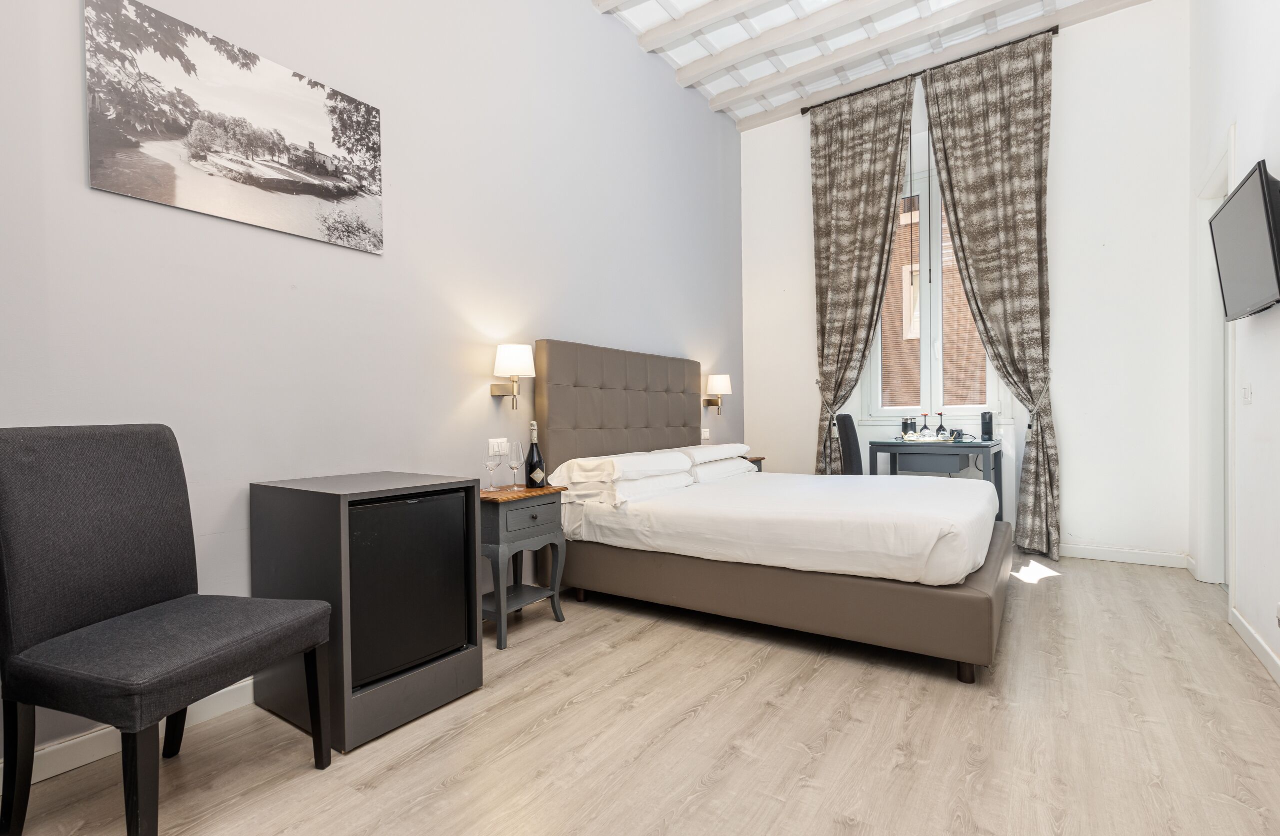 Ett modernt hotellrum med en säng, en tv, en stol och ett skrivbord.