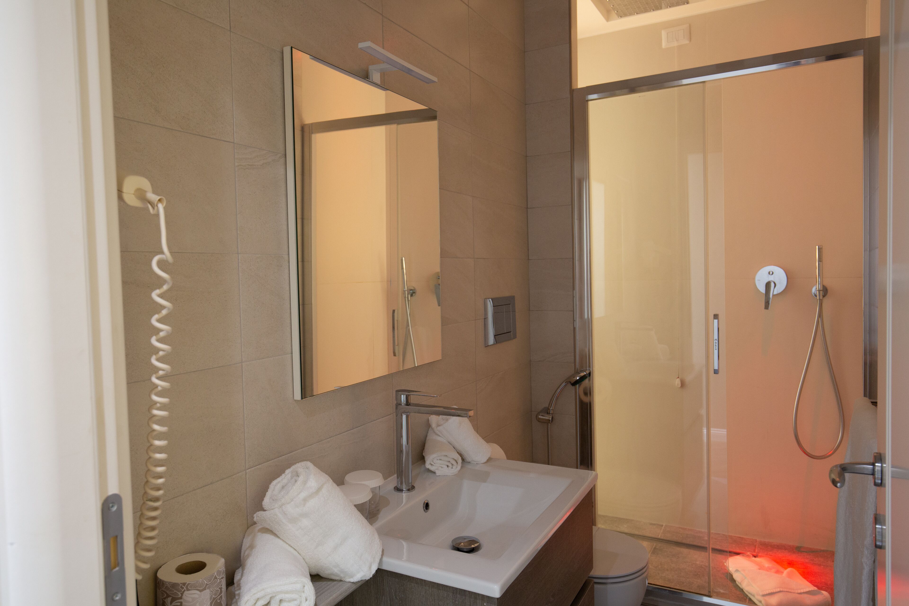 A modern bathroom with a large mirror, a sink, and a shower area.