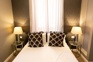 A hotel room with a large bed, two bedside lamps, and patterned pillows. - Spagna Boutique (Rome)