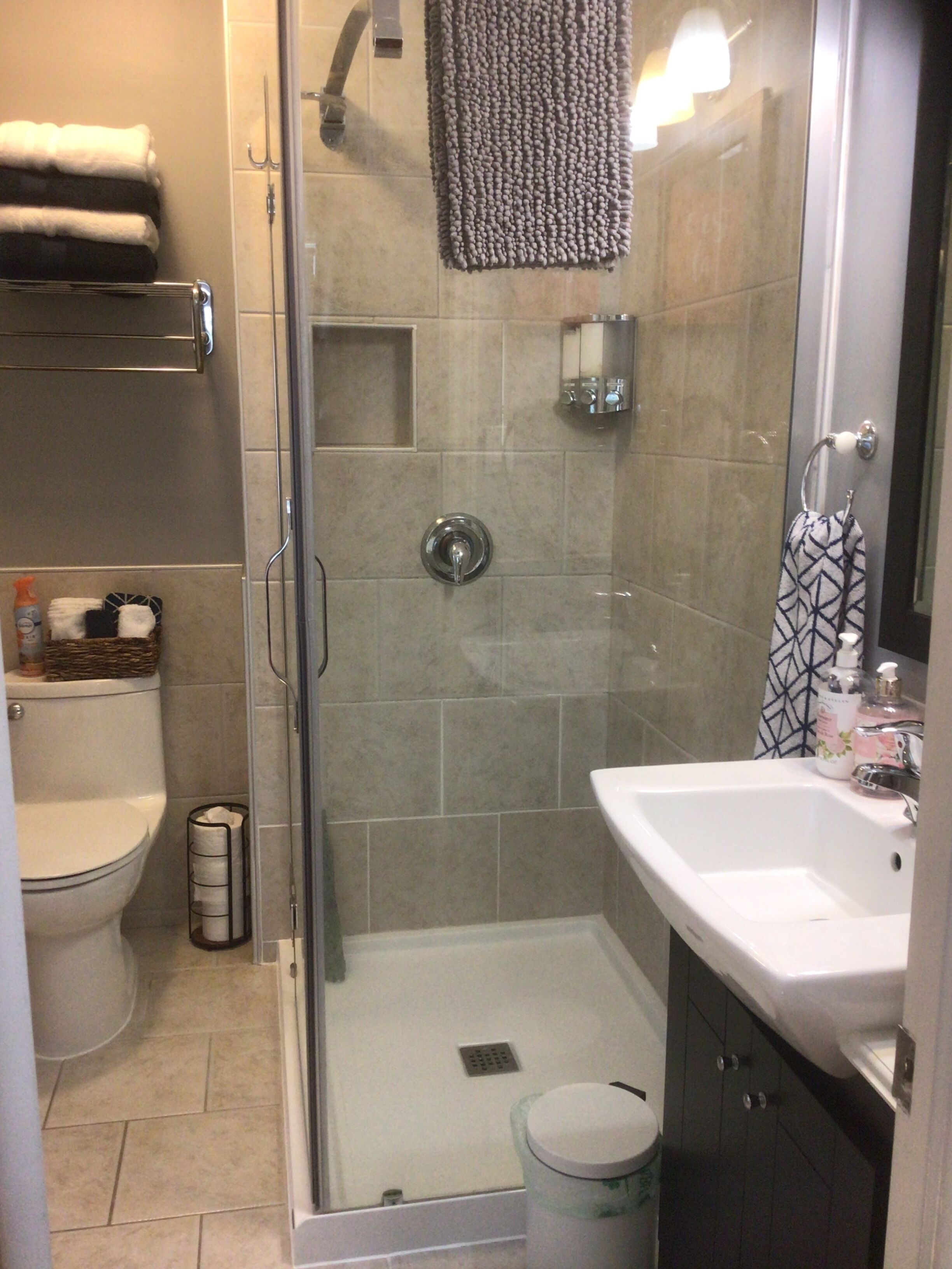 A bathroom with a glass-enclosed shower, a white sink, and a toilet.