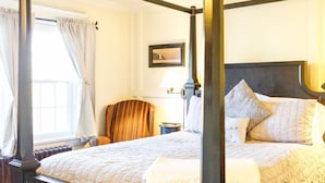 Uma cama de dossel com ventoinha no teto, janela com cortinas e mesa de cabeceira com abajur.