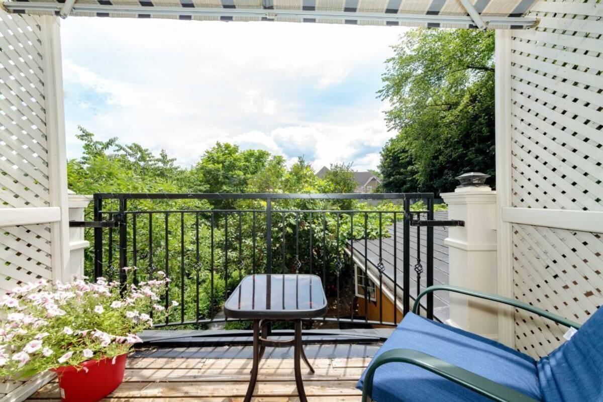 A balcony with a metal railing, a small table, a blue chair, and a red flower pot.