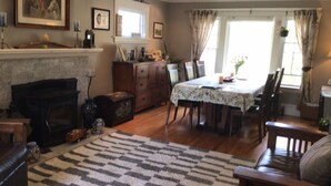 Uma sala de estar aconchegante com lareira, um espaço de jantar com mesa e cadeiras, e uma grande janela com cortinas.
