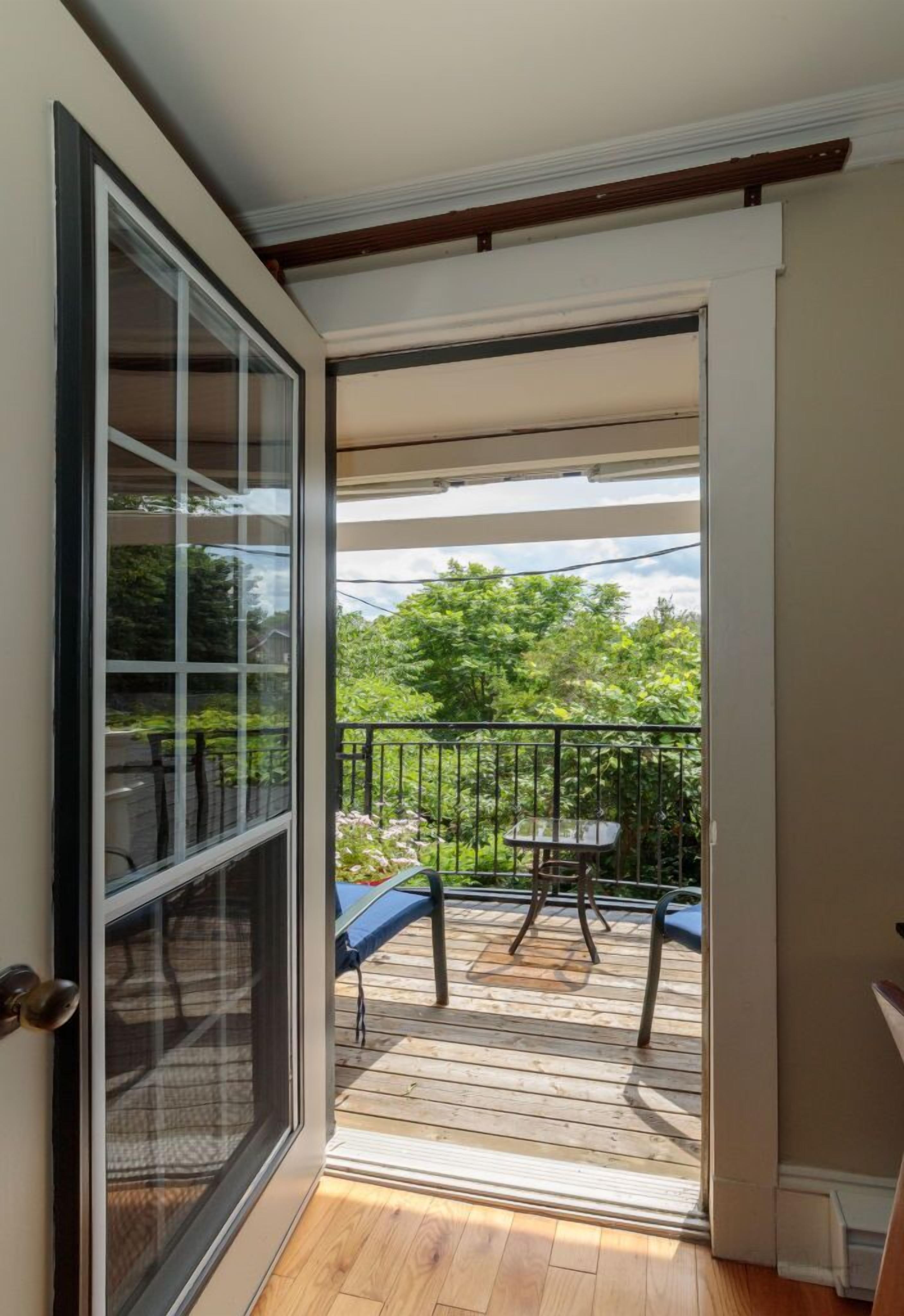 A balcony with a wooden deck, a table, and chairs.
