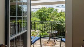 A balcony with a wooden deck, a table, and chairs.