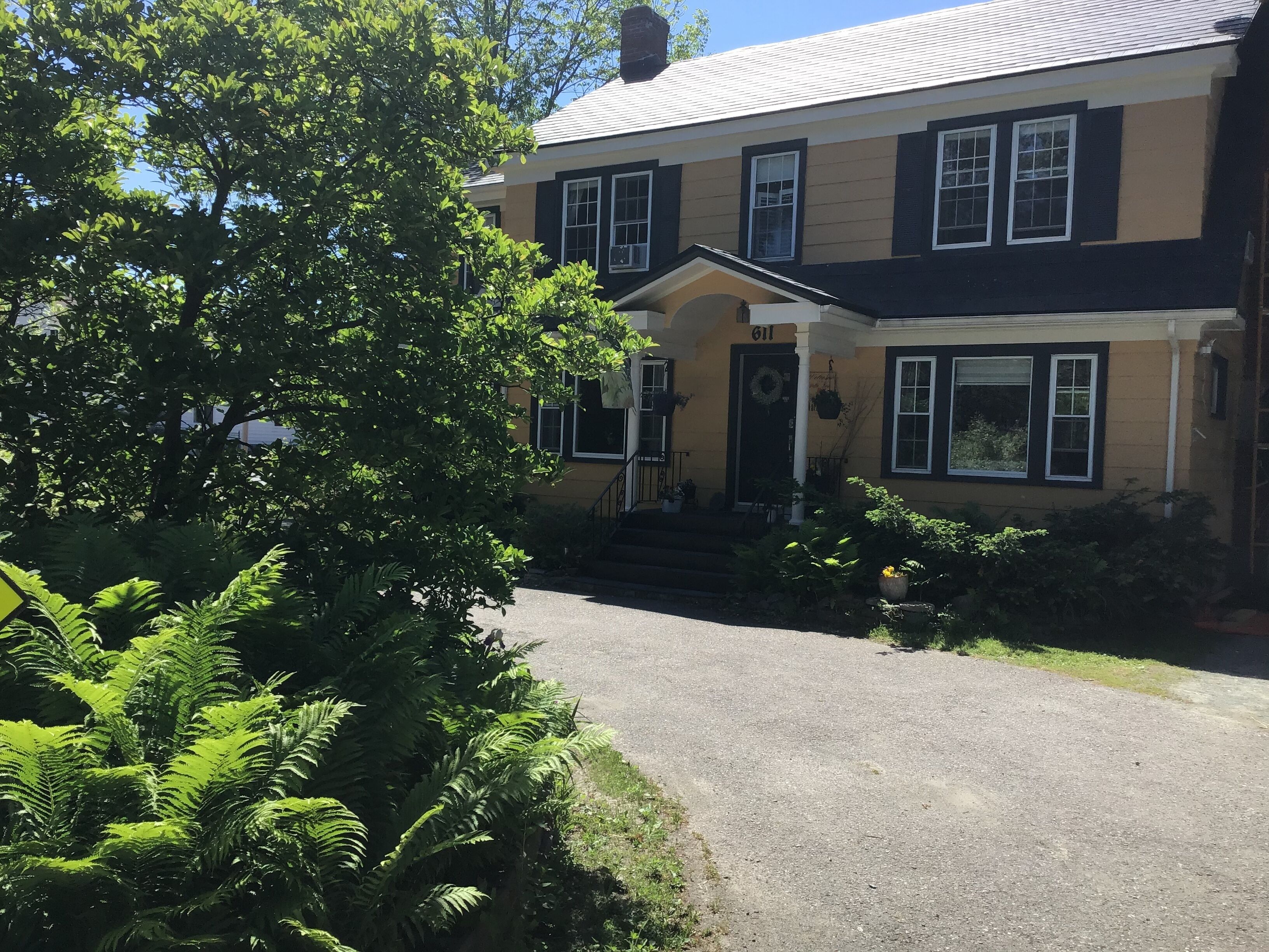 A two-story house with a front porch, a mailbox, and a number '611' on the door.