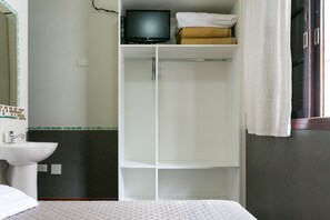 A hotel room with a bed, a white sink, a television, and a wardrobe. - Hotel Residenza (São Paulo)