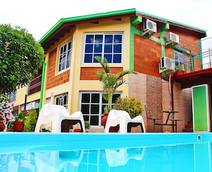 A two-story building with a swimming pool in front. - Reflejos de Luna Llena (Puerto Iguazú)
