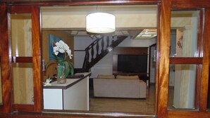 A living room with a sofa, a television, and a vase with flowers. - Hostel Praia Brava (Arraial do Cabo)