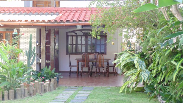 A patio with a table and chairs, surrounded by potted plants and a cactus. - Hostel Praia Brava (Arraial do Cabo)