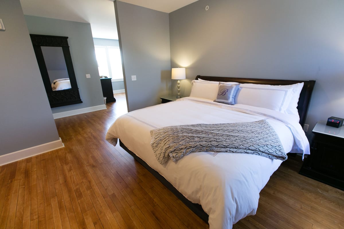 Une chambre à coucher avec un grand lit, une table de chevet, une lampe de chevet et un miroir au mur.