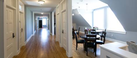A spacious hallway with wooden flooring leading to a dining area with a table and chairs.