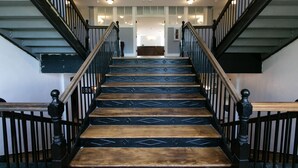 A staircase with wooden steps and black railings, leading to a room with a white door and a chandelier.