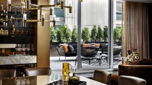 A modern dining area with a glass table, chairs, and a bar area with shelves of glasses and bottles. - Bisha, a Luxury Collection Hotel Toronto (Toronto)