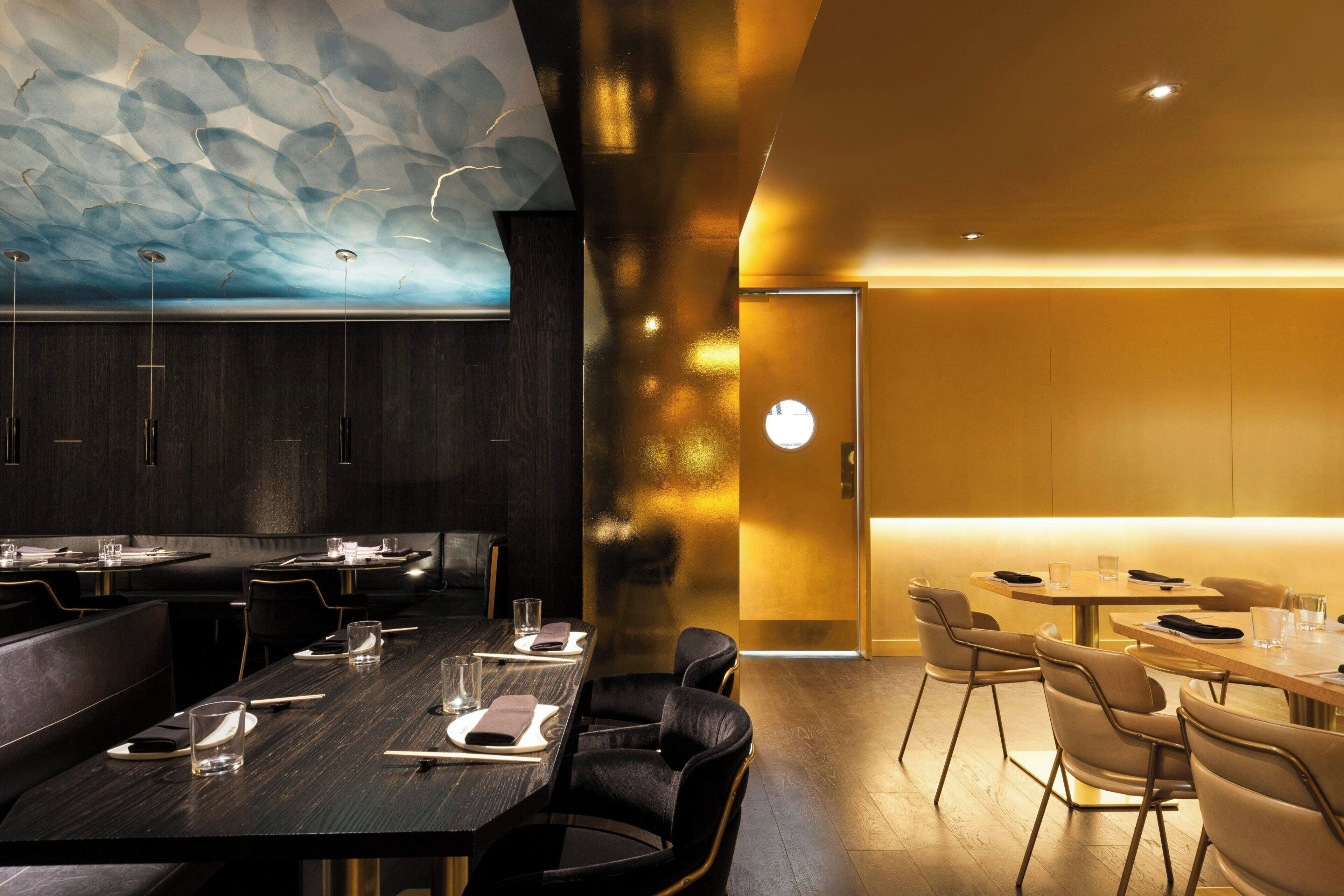 A modern restaurant interior with dark wood tables, leather seating, and a unique ceiling design.
