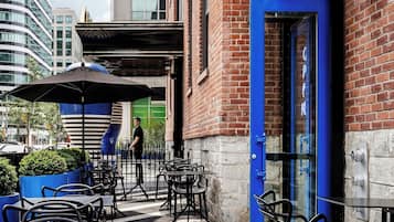 Un café al aire libre con mesas y sillas, una puerta azul y un letrero que dice "French Made".