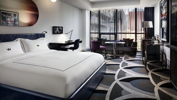 A modern hotel room with a large bed, a desk, a chair, and a view of the city through large windows. - Bisha, a Luxury Collection Hotel Toronto (Toronto)