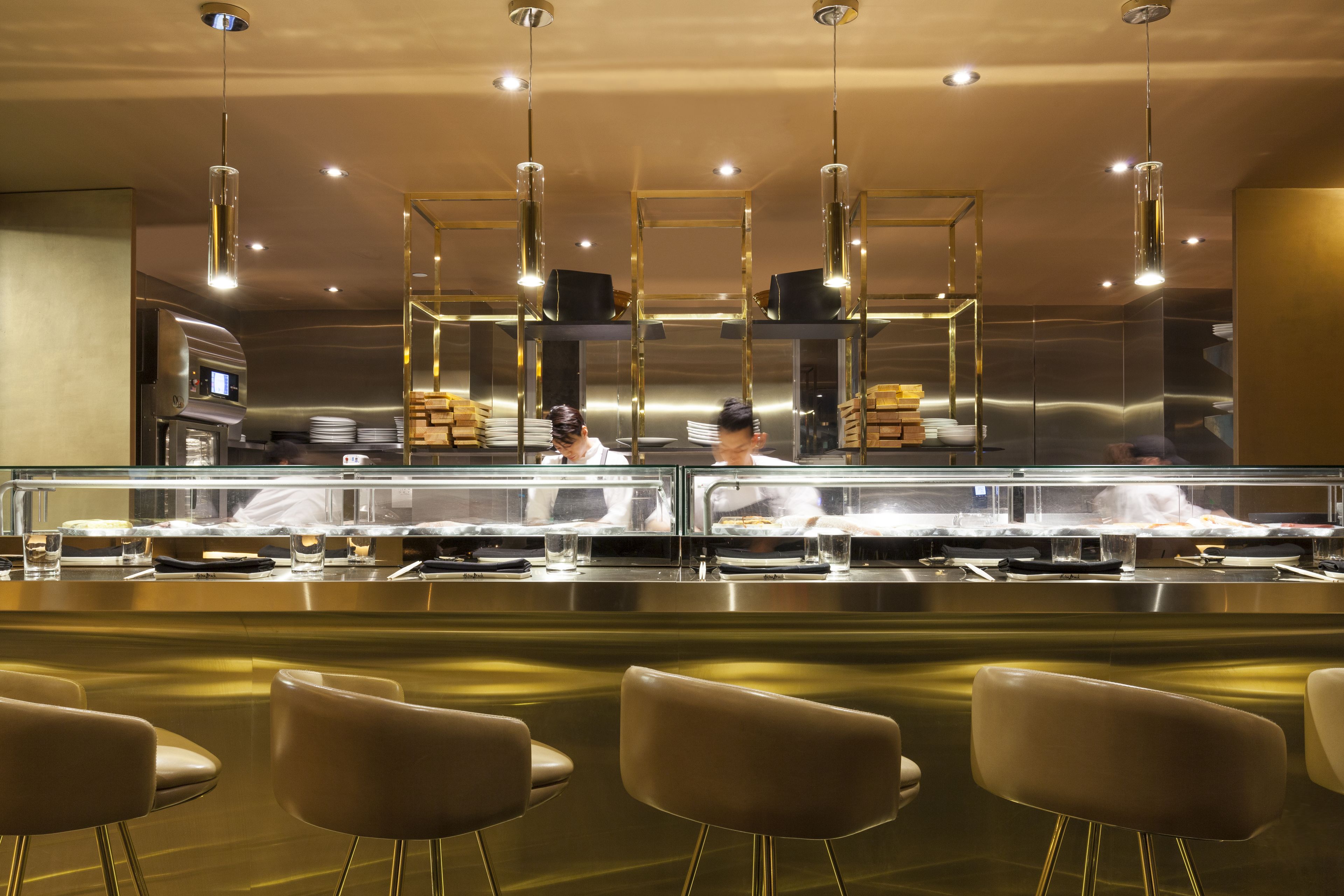Una cucina moderna con elettrodomestici in acciaio inossidabile, una vetrina e sedute da bar contemporanee.