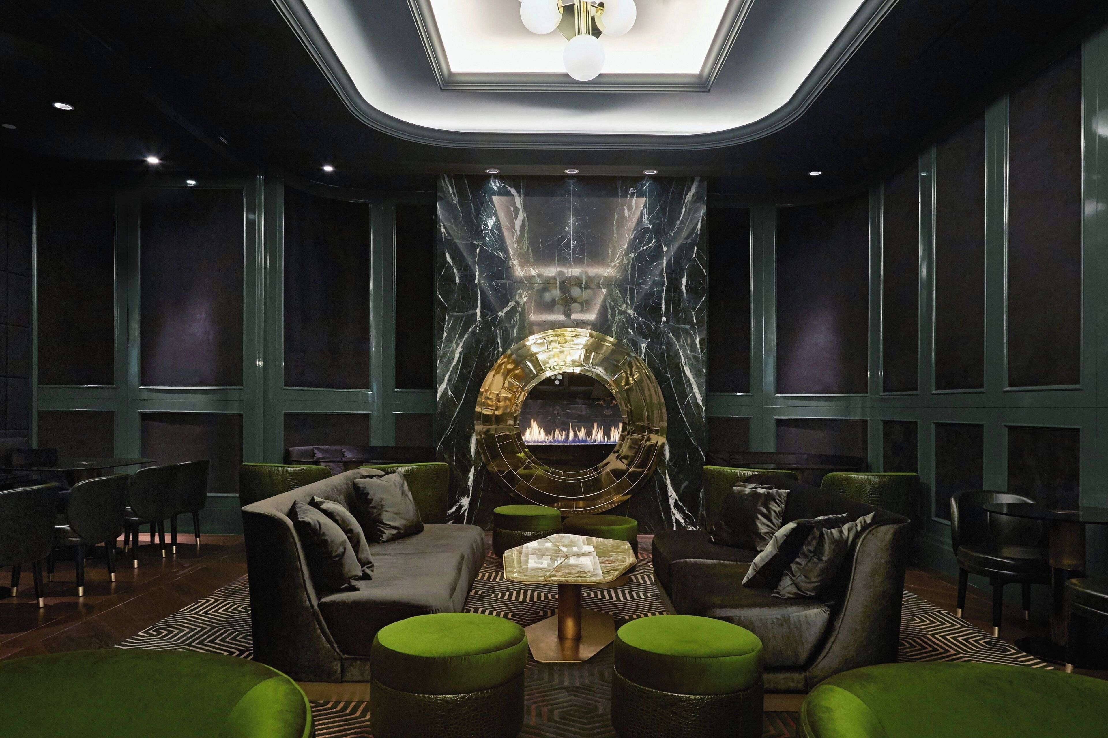 A modern lounge area with a central fireplace, comfortable seating, and a patterned floor.