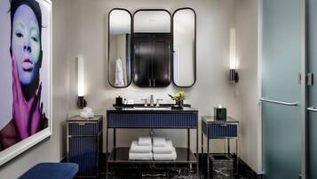 A modern bathroom with a large mirror, two sinks, a bench, and a marble floor.