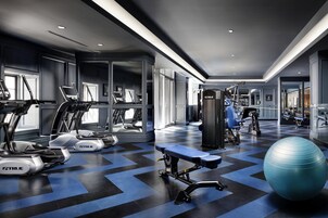 Een moderne sportschool met loopbanden, een bankdrukpers en fitnessballen.