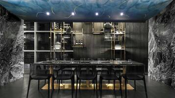 Un comedor moderno con una mesa larga, sillas negras y un diseño de techo singular.