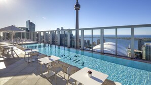 A rooftop pool with a city skyline view, including a tower resembling the CN Tower, and tables and chairs for relaxation. - Bisha, a Luxury Collection Hotel Toronto (Toronto)