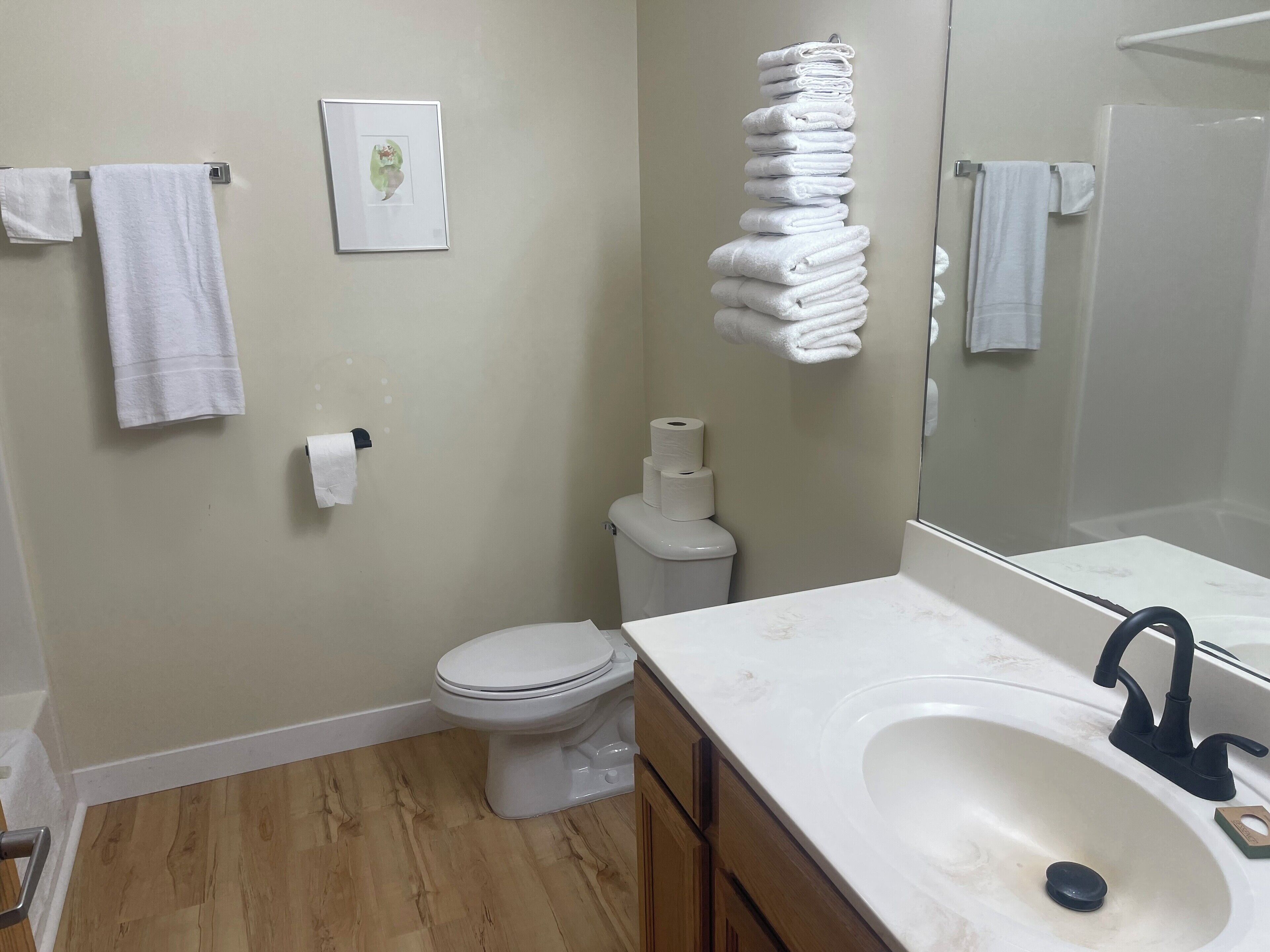 Un baño con inodoro, lavabo y toallas apiladas.