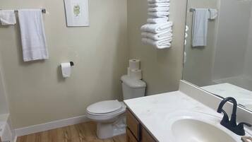 Un baño con inodoro, lavabo y toallas apiladas.