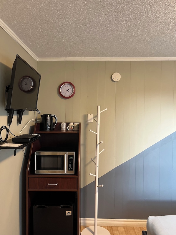 Una habitación con microondas, cafetera y un reloj en la pared.