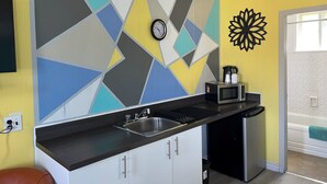 Eine moderne Küche mit geometrischer Spritzschutzleiste, einer Uhr und einer Kaffeemaschine auf der Arbeitsplatte.