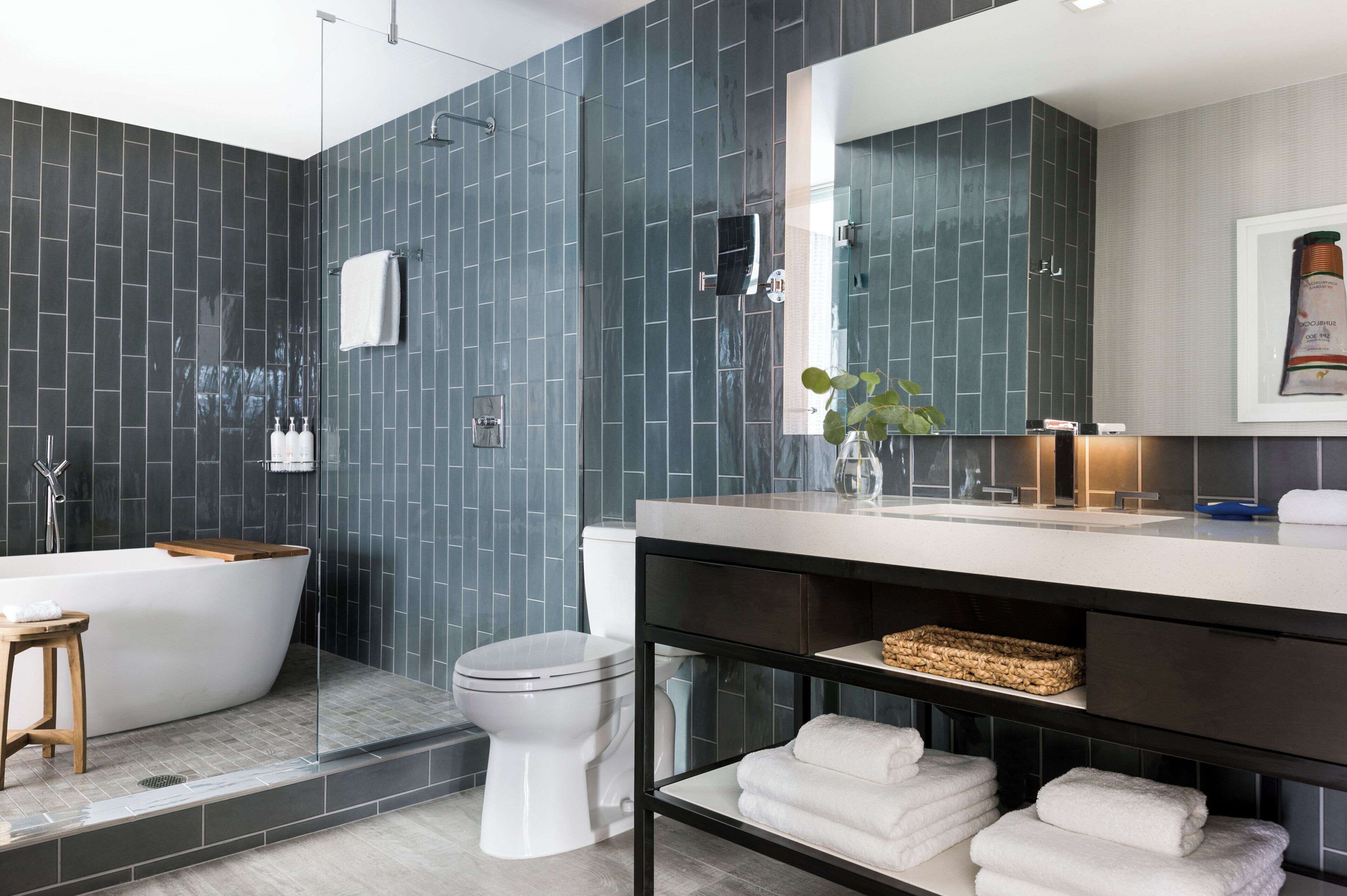 A modern bathroom with a freestanding bathtub, a toilet, and a vanity with a mirror.