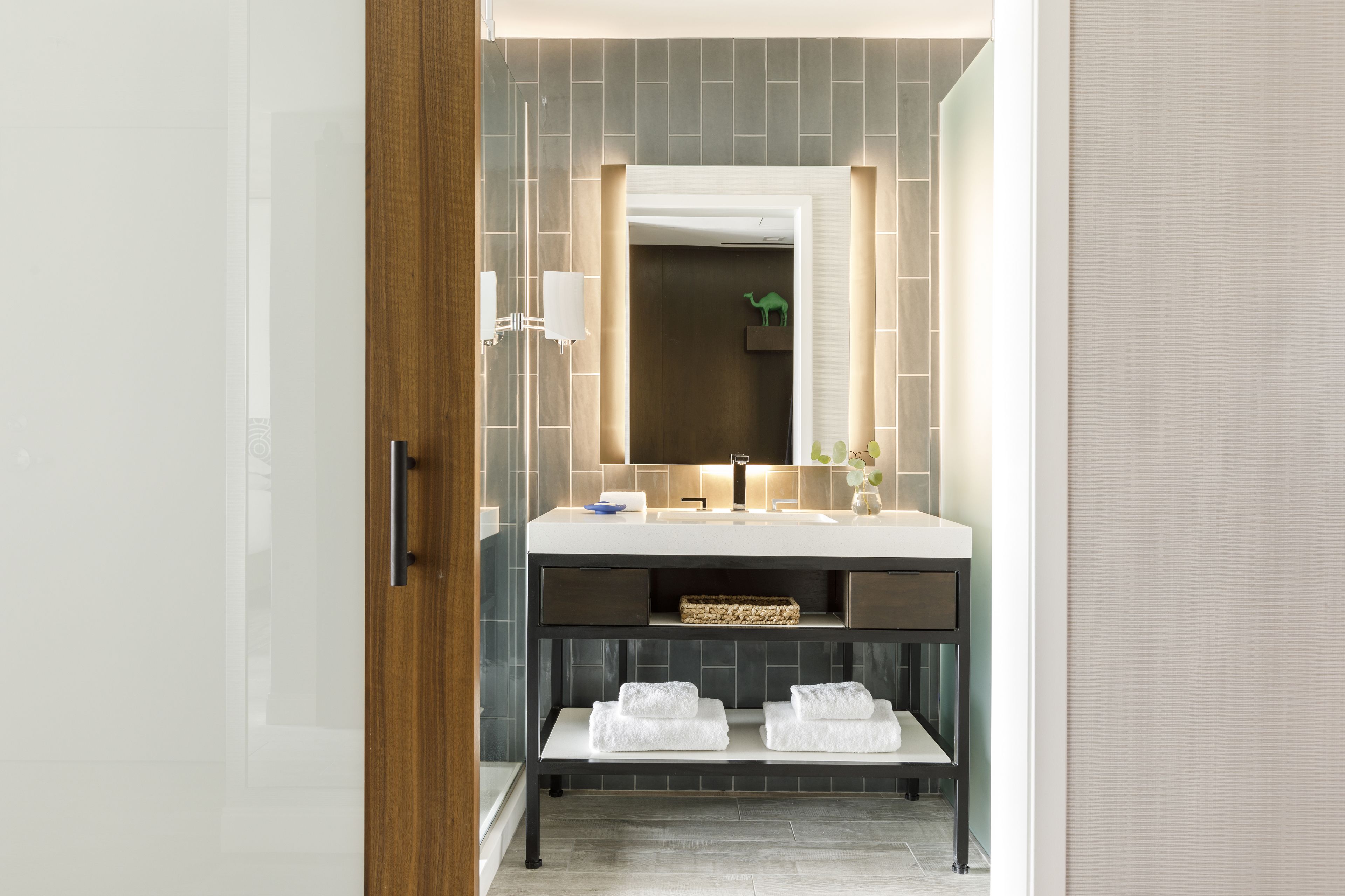 Un baño moderno con un espejo grande, un lavabo y un estante con toallas.