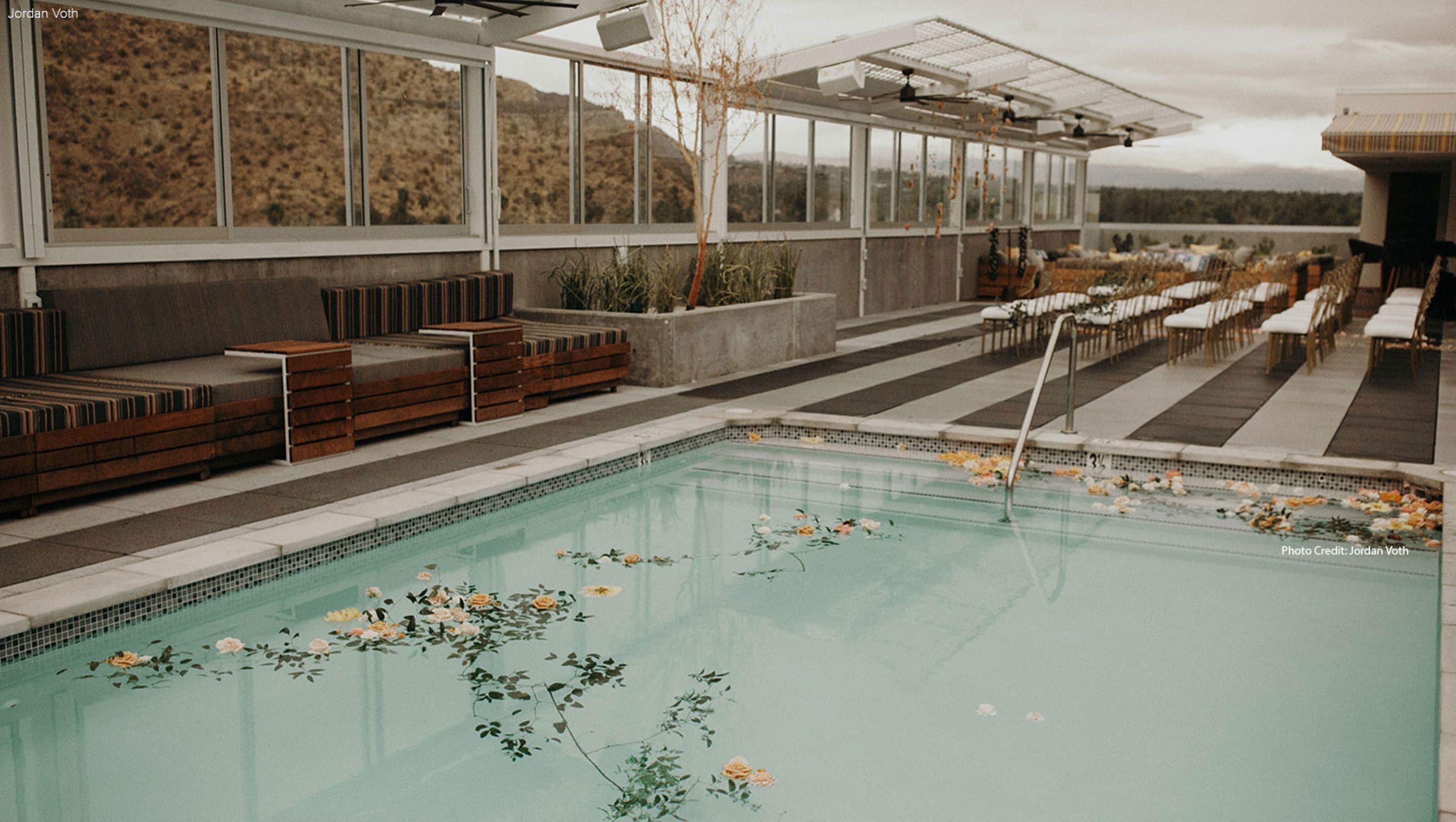 Une piscine agrémentée de compositions florales, de coins salon et d’une terrasse couverte offrant une vue sur les collines.
