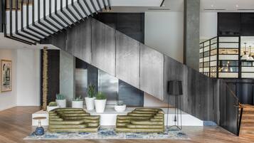 Un interior modern amb una escala, otomans de cuir, plantes en testos i un disseny minimalista.