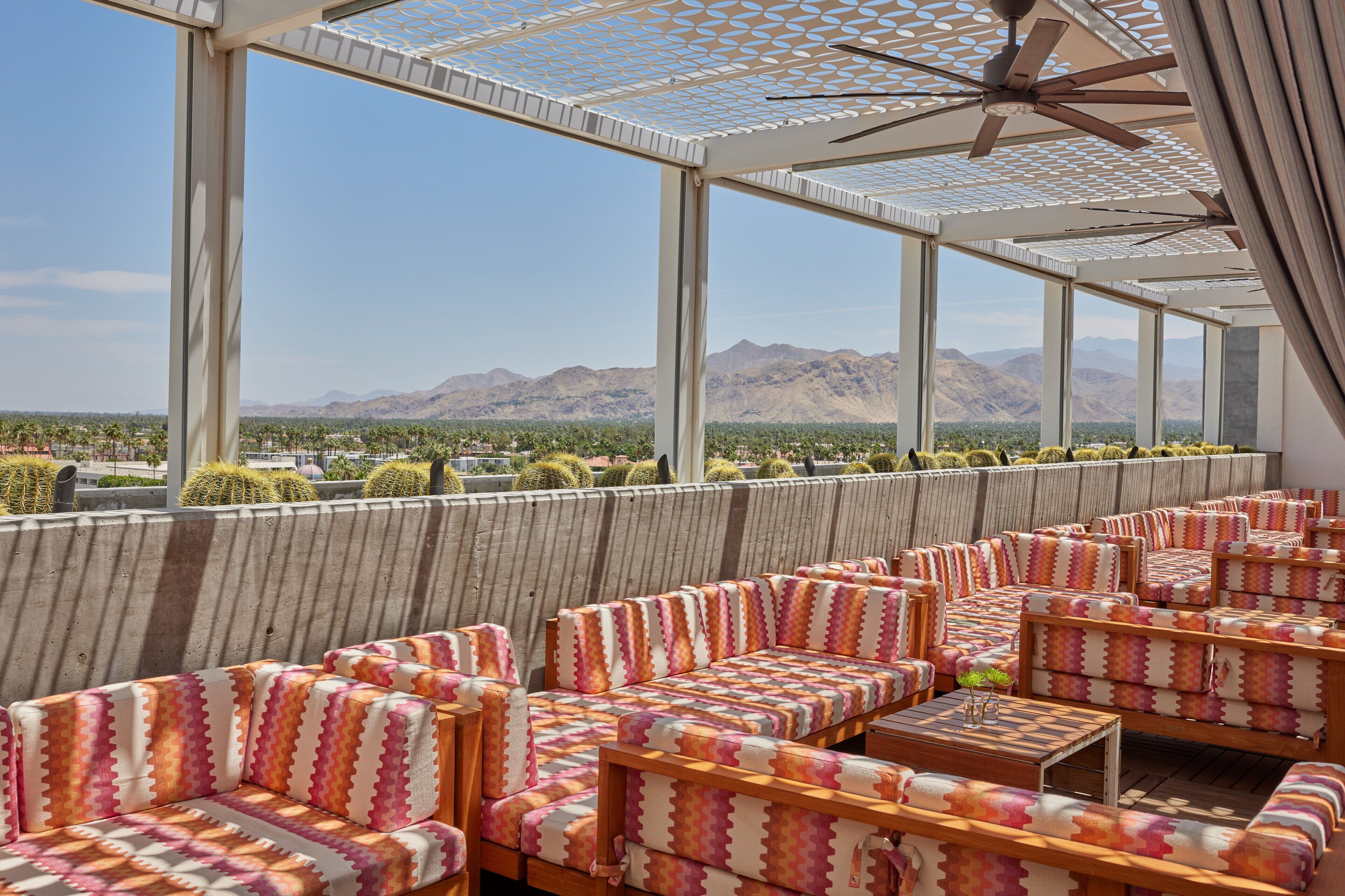 A covered outdoor seating area with patterned cushions and a view of mountains.