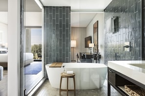 Un baño moderno con una bañera independiente, un espejo grande y un tocador con lavamanos.