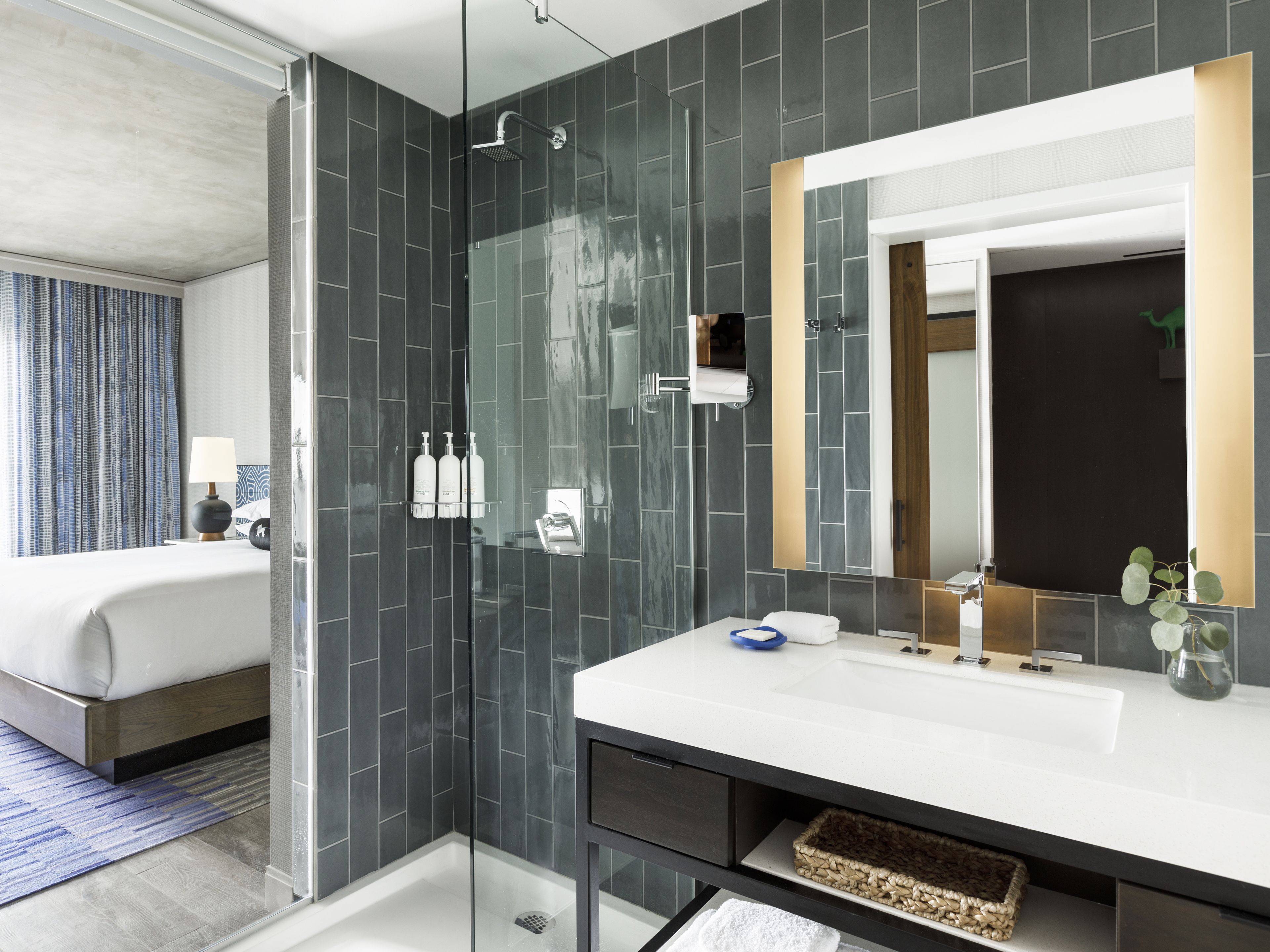 A modern bathroom with a glass-enclosed shower, a large mirror, and a white sink.