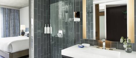 A modern bathroom with a glass-enclosed shower, a large mirror, and a white sink.