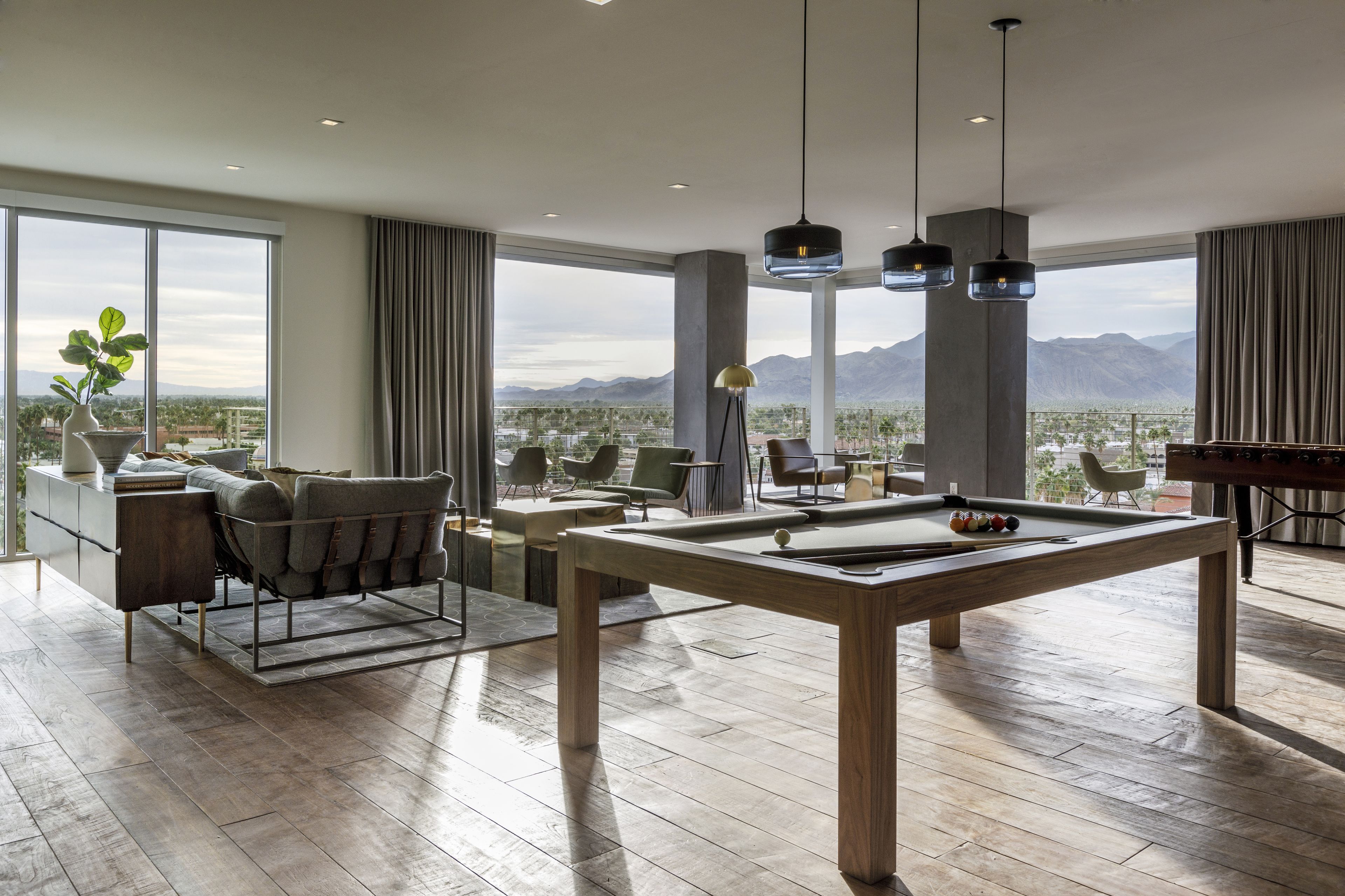 Amplia habitación con mesa de billar, asientos cómodos y grandes ventanales con vistas a la montaña.