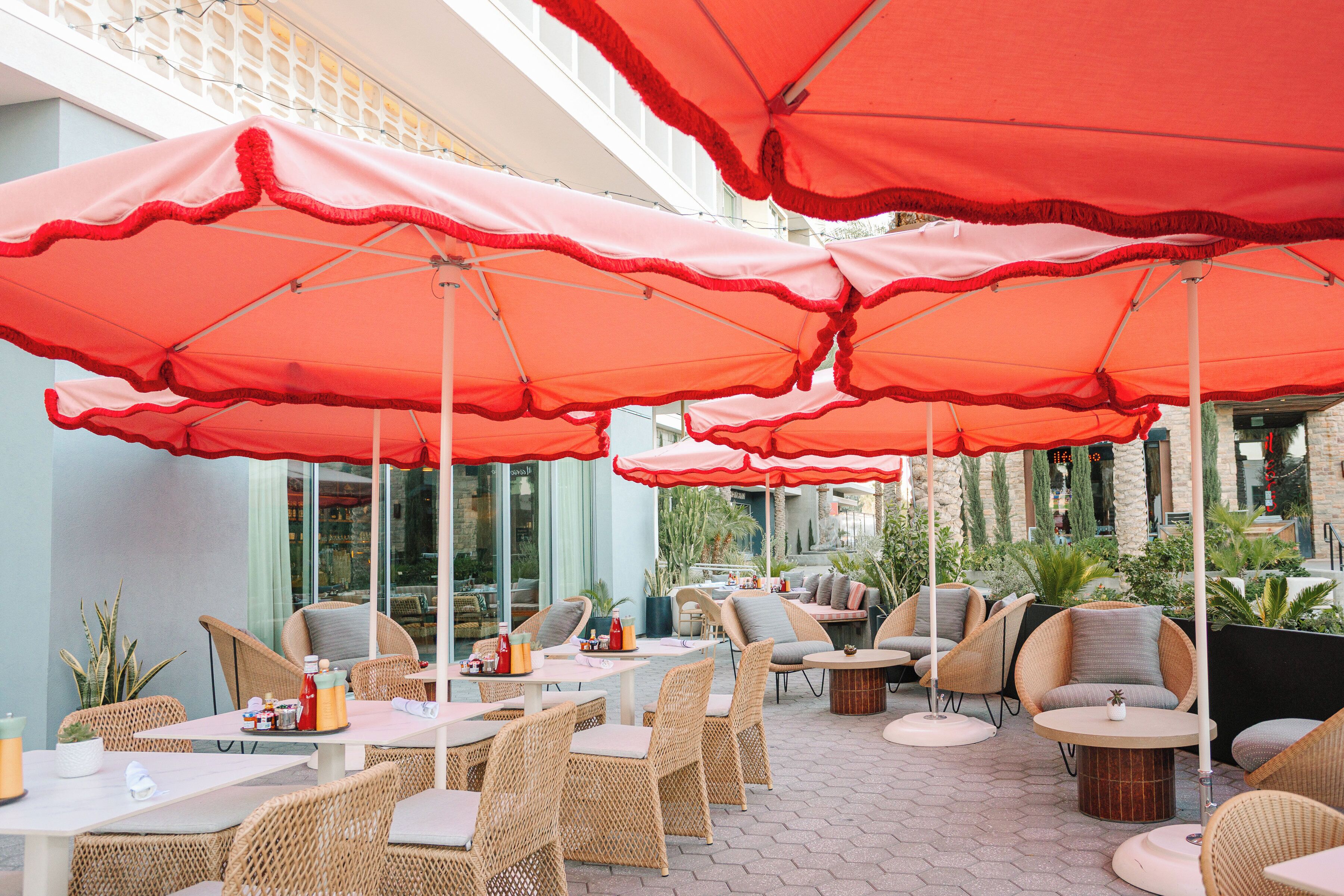 An outdoor seating area with wicker furniture and red umbrellas.