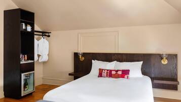 Une chambre d’hôtel avec un grand lit, une armoire, un mini-bar et une étagère fixée au mur.