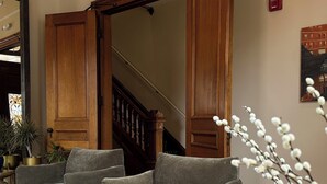 A living room with a grey sofa set, a wooden staircase, and a potted plant. - The Francis (Portland)