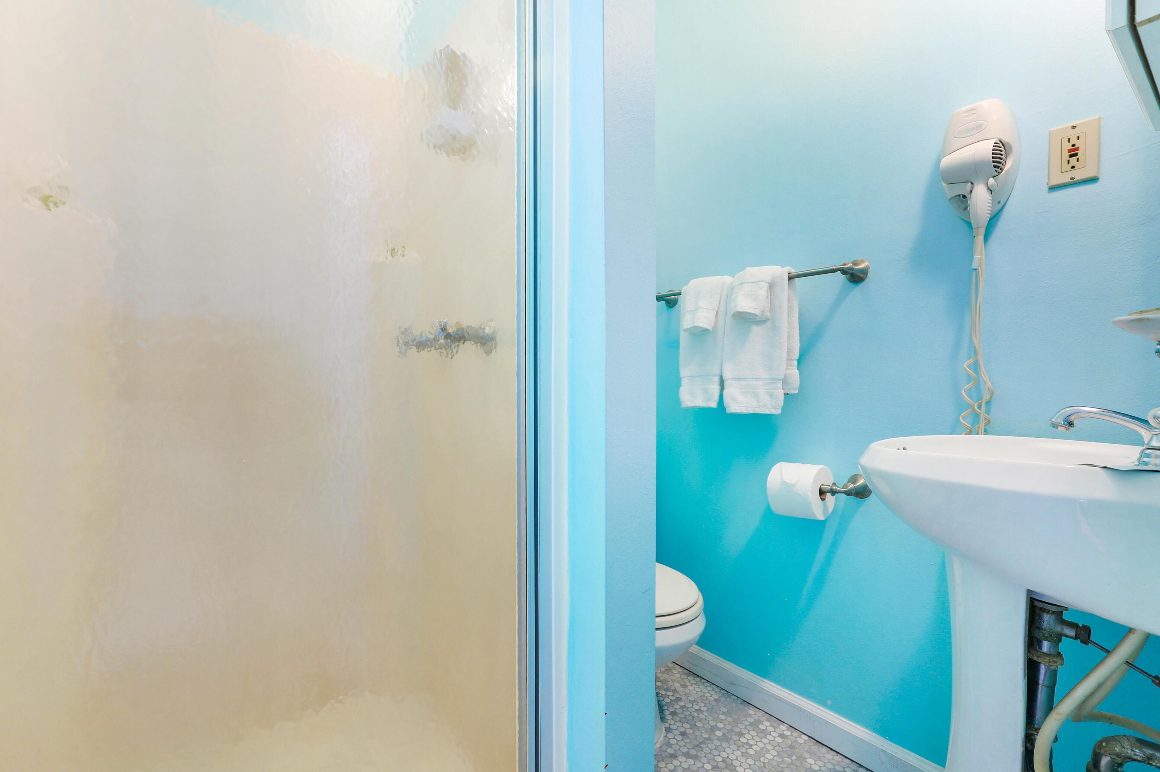 A bathroom with a blue wall, a white sink, a hair dryer, and a towel rack.