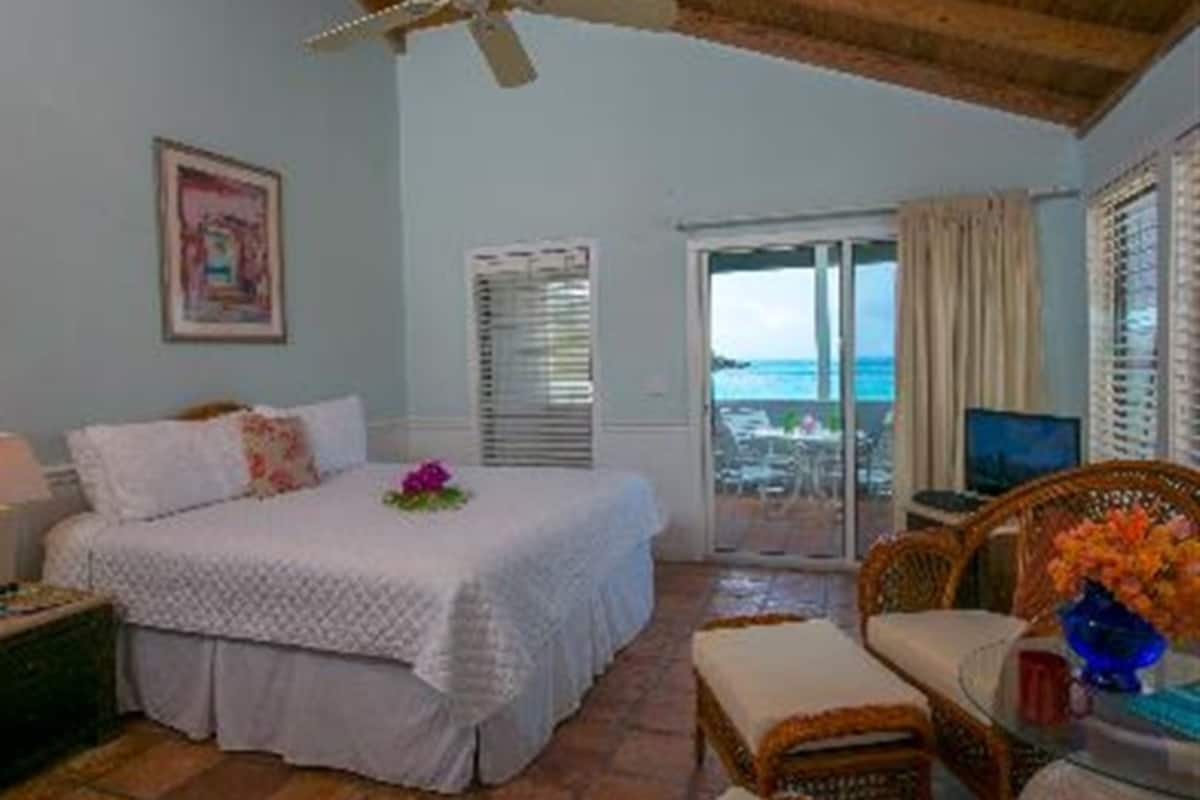 A bedroom with a bed, a desk, a chair, a window with a view, and a ceiling fan.